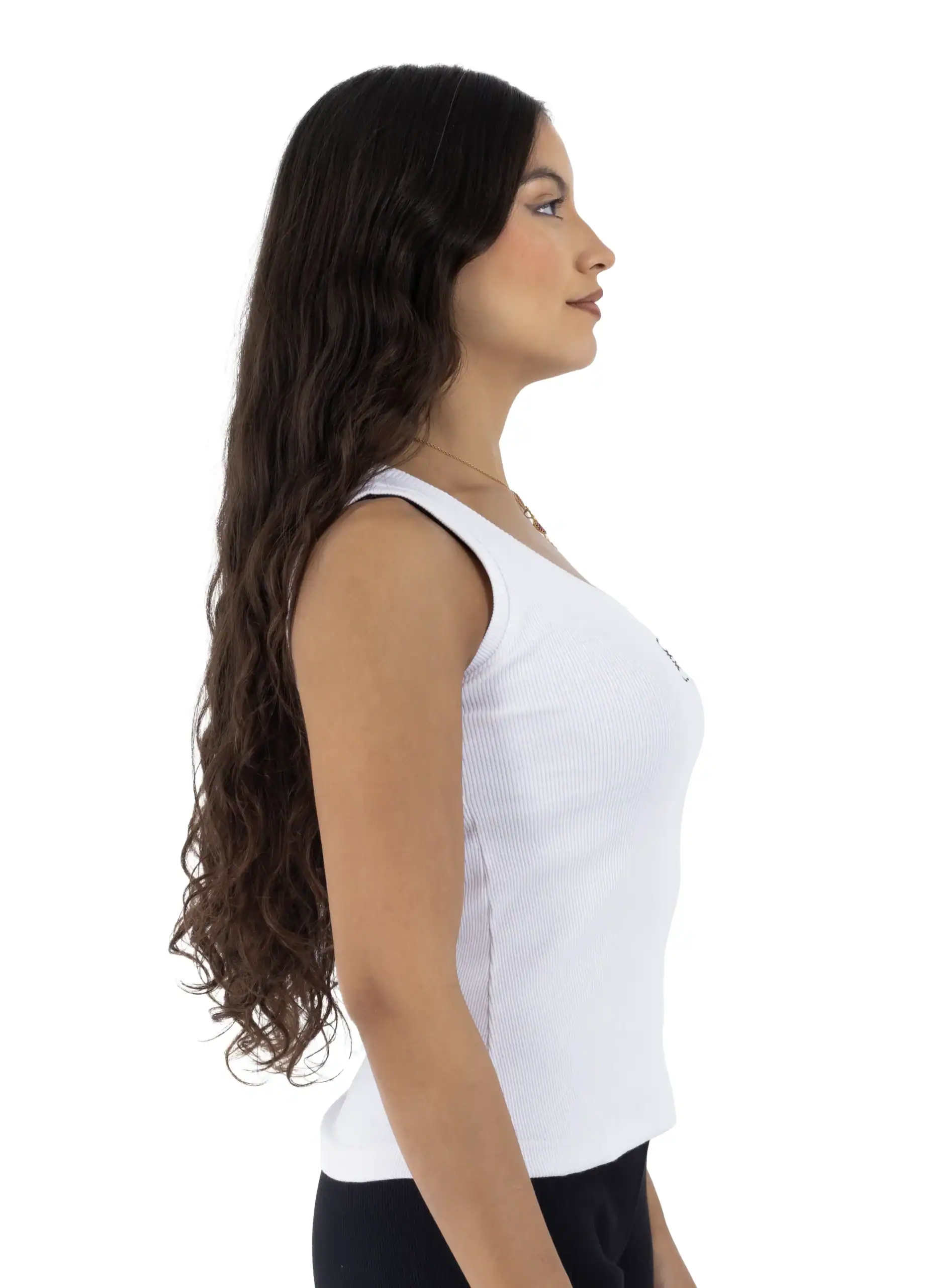 Side view of a woman wearing a white tank top and black pants.
